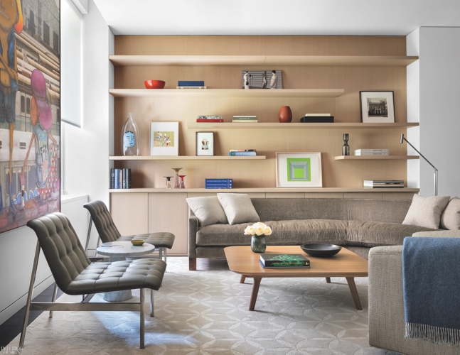 Chiếc ghế sofa bọc nệm màu lông chuột cùng những chiếc gối tựa êm ái kết hợp với sách và tranh ảnh tạo nên không gian thư giãn đẳng cấp.