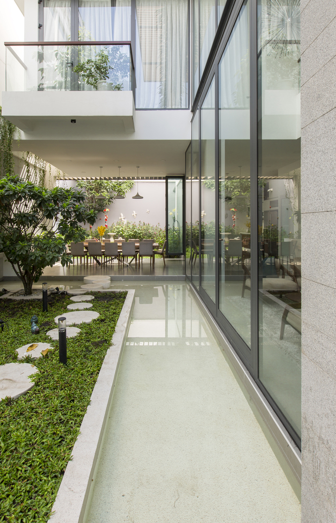 Để các không gian chức năng đều có view nhìn ra sân vườn, các kiến trúc sư đã thiết kế những bức tường kính cường lực. Tường kính giúp xóa nhòa ranh giới giữa bên trong và ngoài nhà, mang không gian sân vườn vào trong nhà và ngược lại.